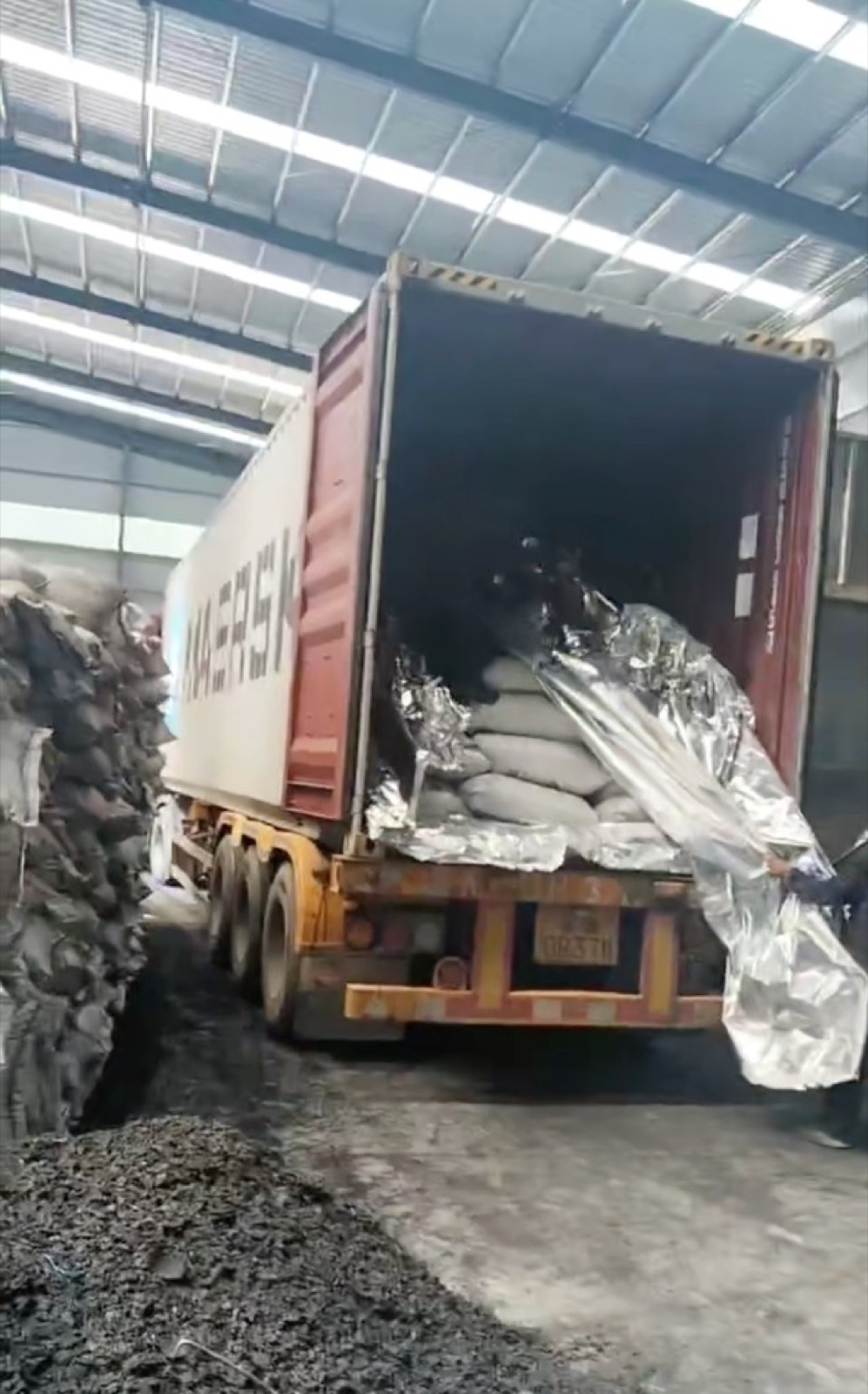 Shipping container opened for unloading bagged coconut shell charcoal at a Chinese factory