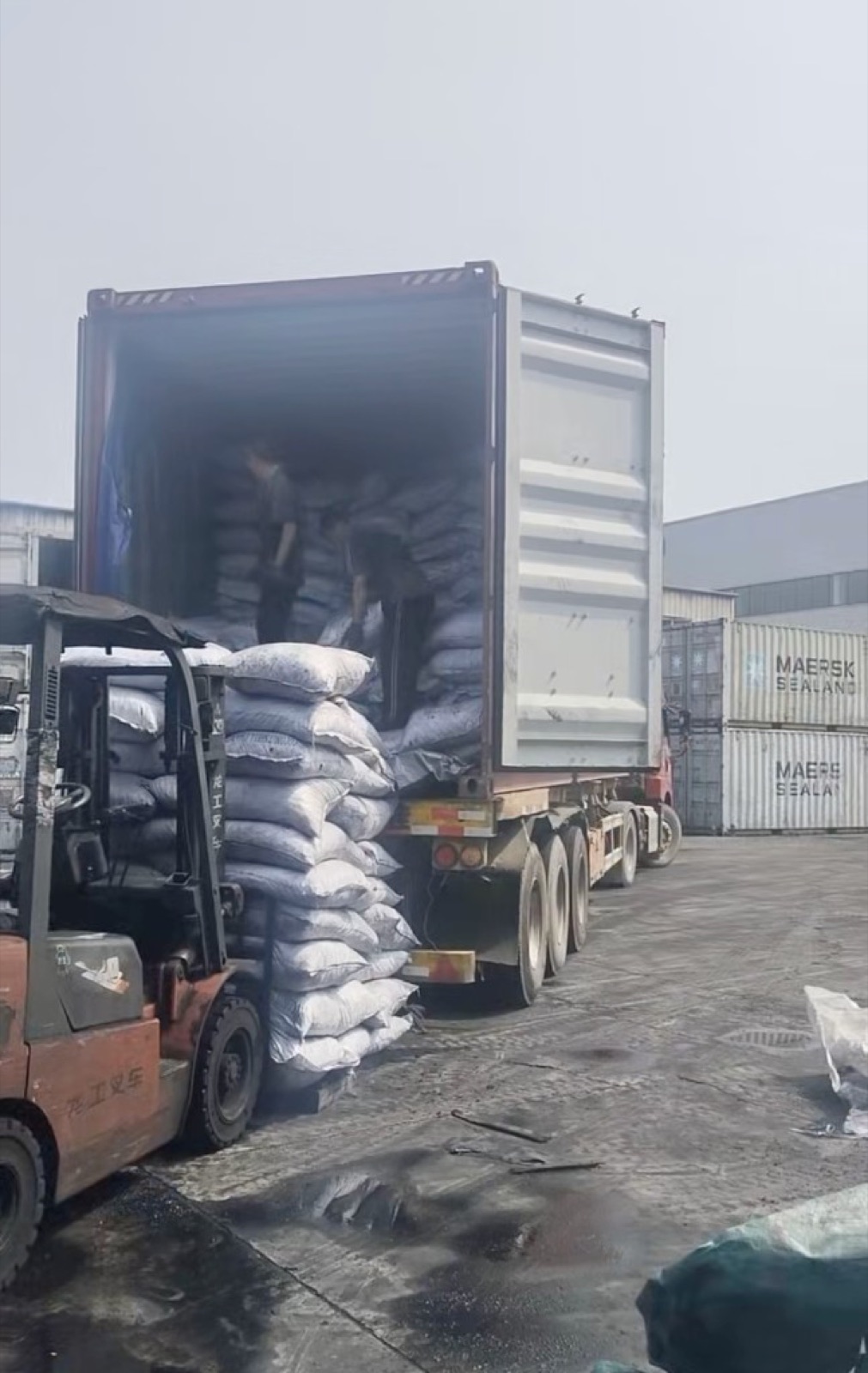Forklift unloading bagged imported coconut shell charcoal from a container
