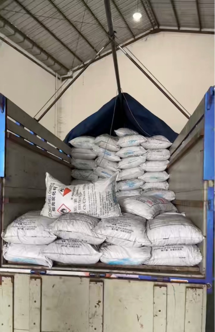 Bagged coconut shell charcoal loaded into a shipping container in Jakarta